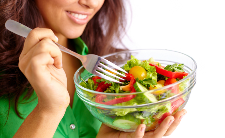Closeup view of woman holding a bowl of salad and fork