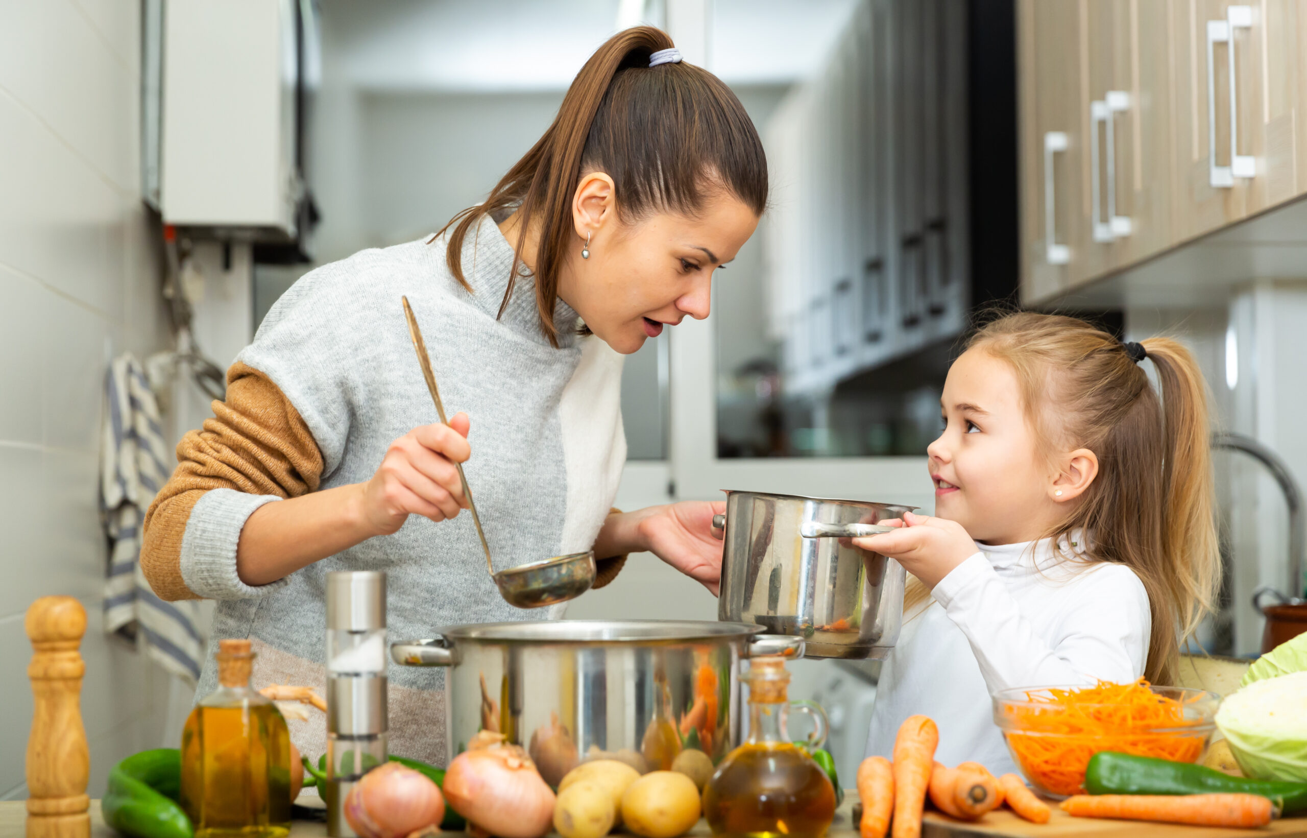 Mother and daughter cooking a soup together at home