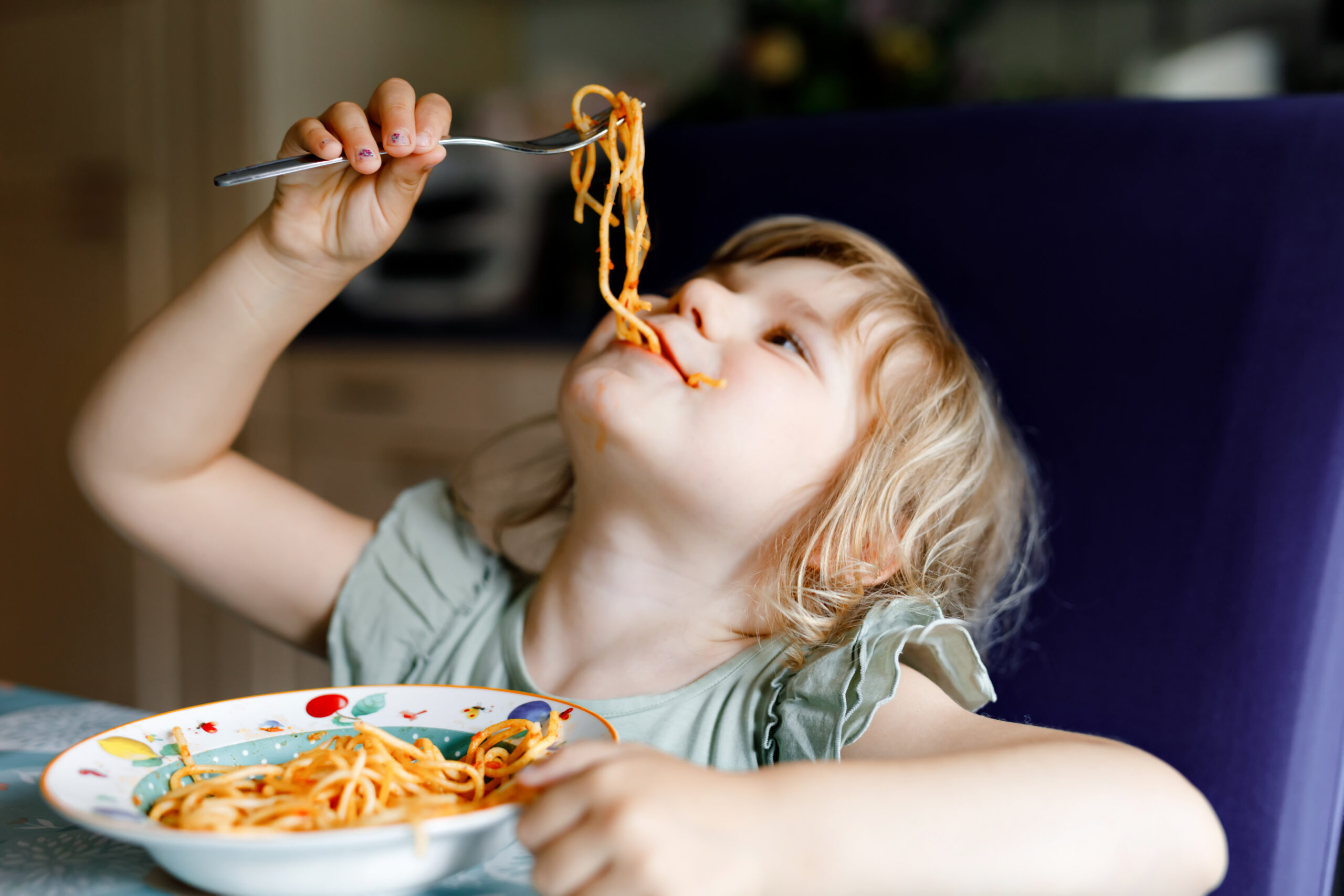 Toddler eating spaghetti at the table