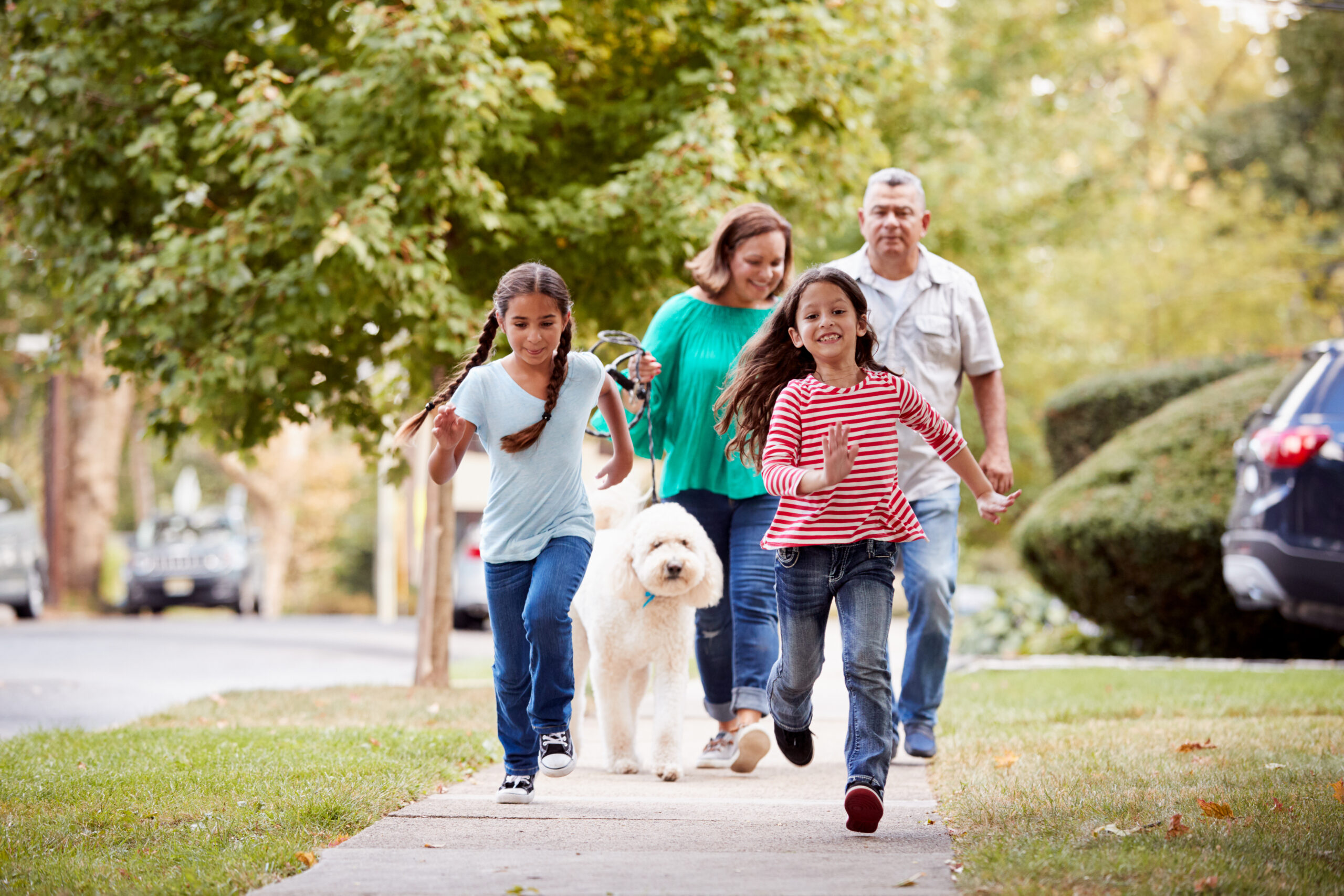 Grandparent walking a dog while two granddaughters run